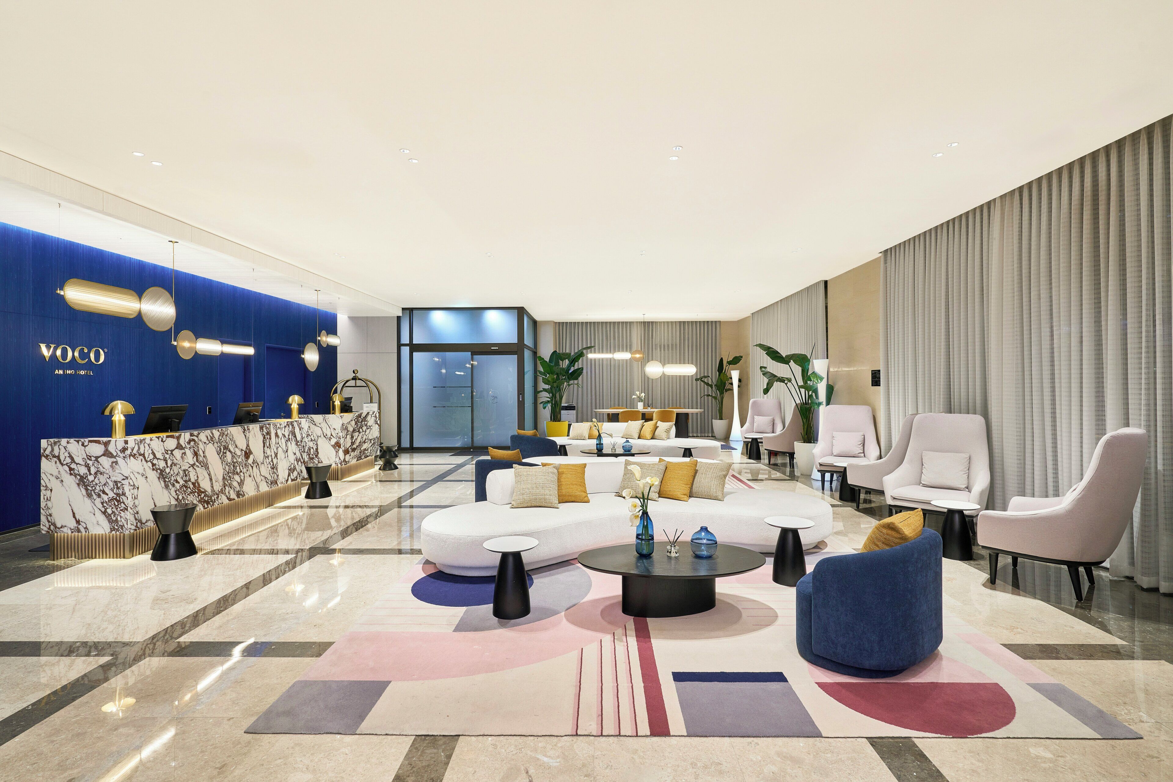 Un moderno vestíbulo de hotel con mostrador de recepción, zona de estar y un amplio ventanal.