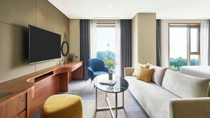 A modern hotel room with a flat-screen TV, a sofa, a coffee table, and a chair. - voco Seoul Myeongdong by IHG (Seoul)