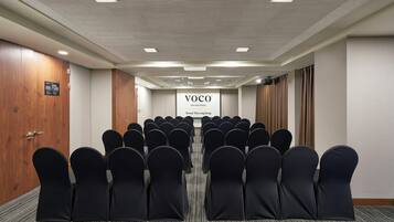 A conference room with rows of chairs facing a screen, a wooden door, and a sign indicating it's a hotel.