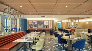 Ein modernes Restaurant mit Sitzecken, runden Tischen und einem gemusterten Boden.