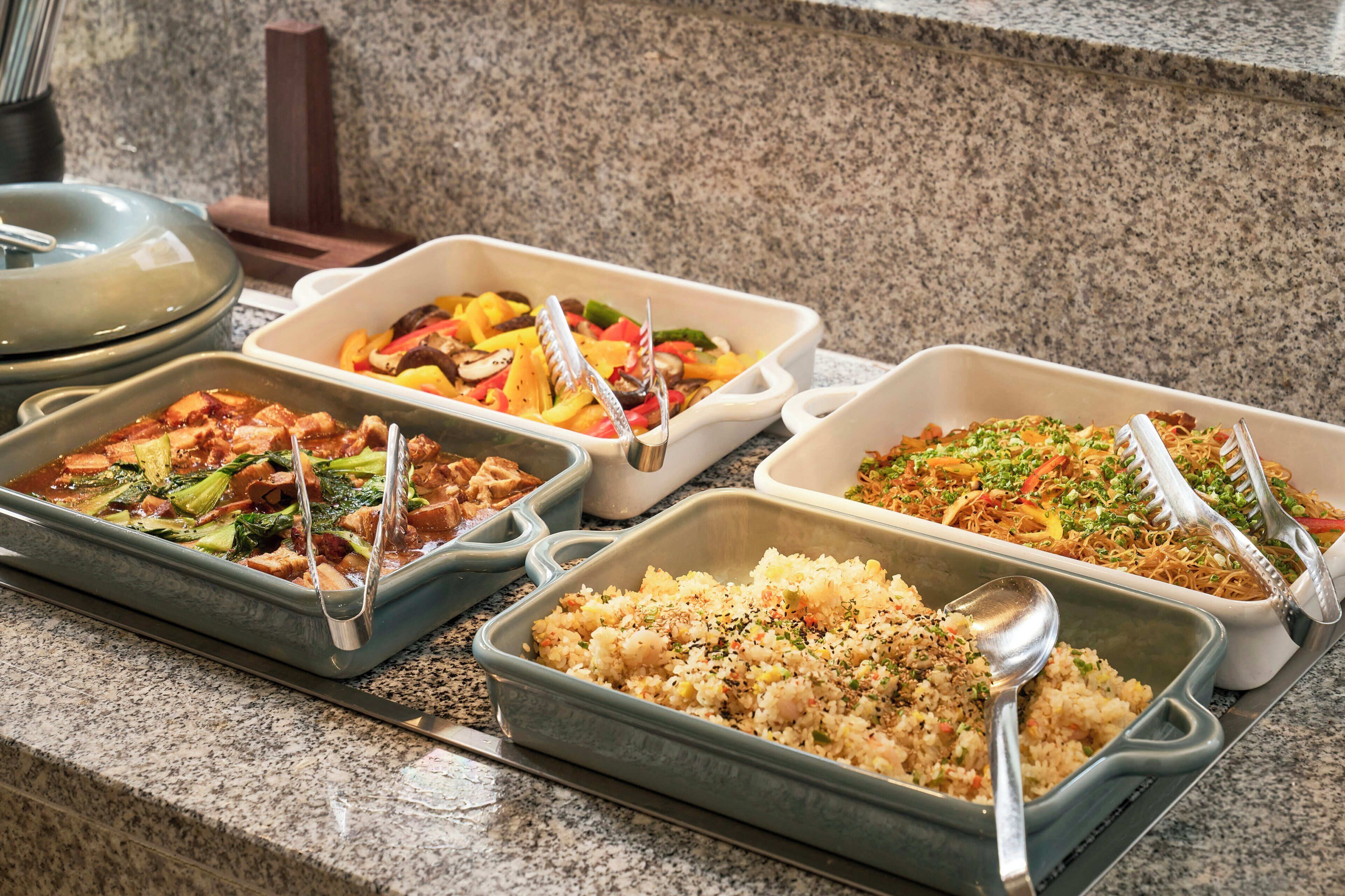 A buffet with various dishes including rice, vegetables, and meat.