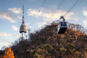 A cable car system on a hill with a tower in the background. - voco Seoul Myeongdong by IHG (Seoul)