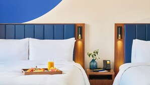 Habitación de hotel con dos camas, una bandeja de desayuno, un florero y un teléfono en la mesita de noche.