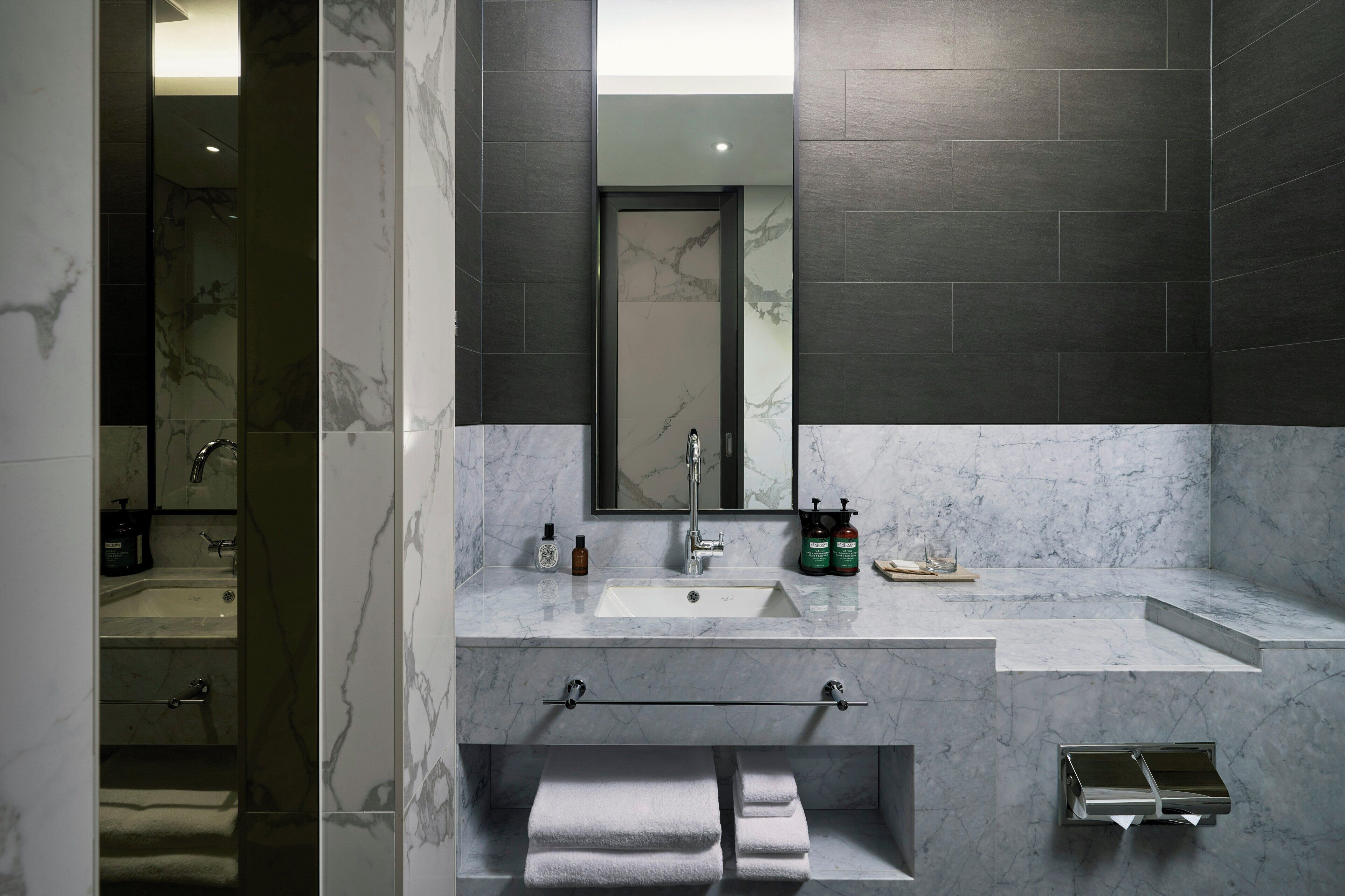 A modern bathroom with a marble sink, a towel rack, and a mirror.