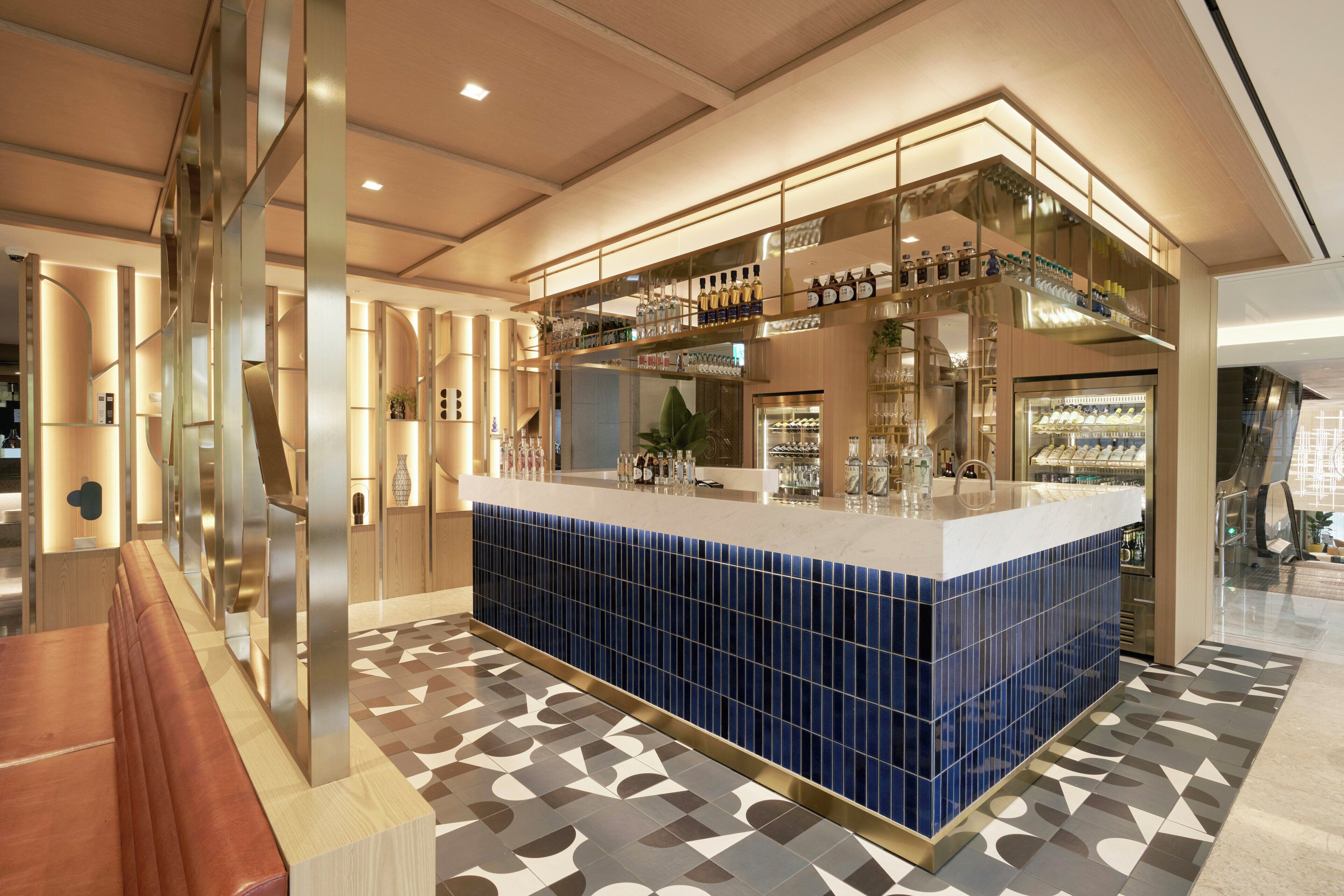 A modern bar area with a blue-tiled counter, glassware, and bottles.