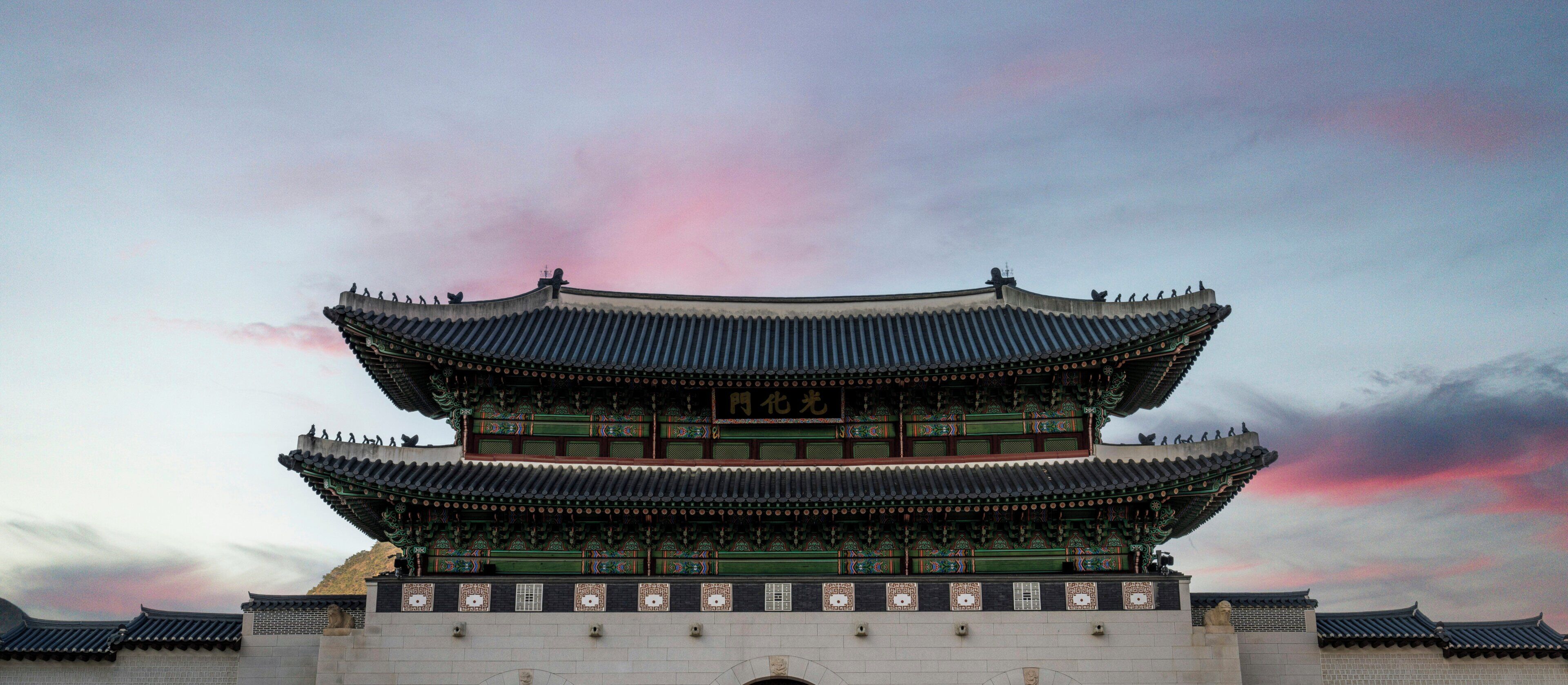 A traditional multi-tiered building with ornate roof decorations and a stone base.
