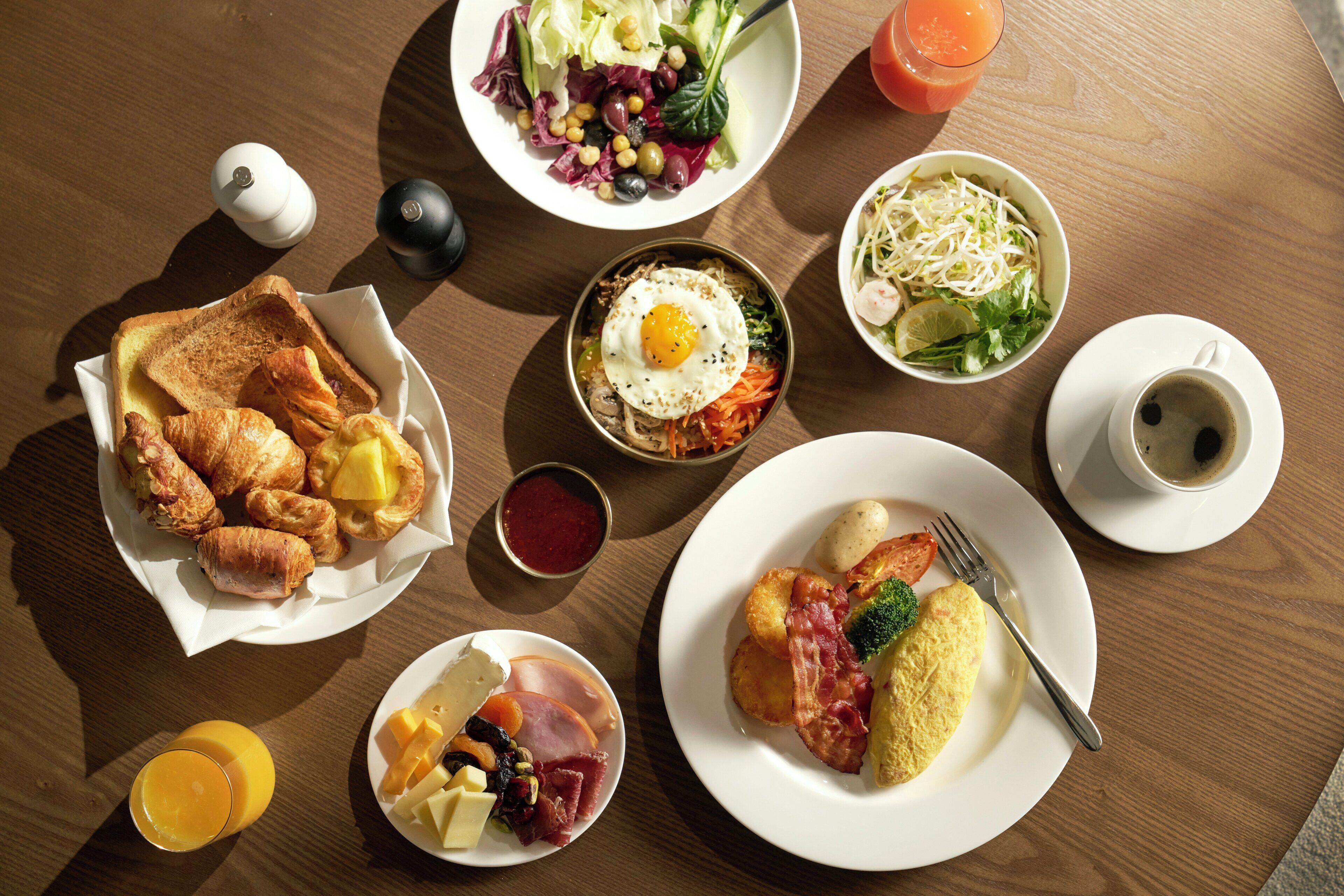 A breakfast table with various dishes including toast, eggs, ham, cheese, and a salad.