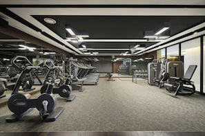 A modern gym with various exercise equipment, including treadmills and weight machines, arranged in a spacious layout.