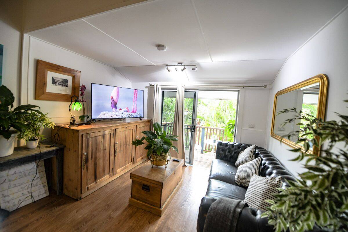 Ein Wohnzimmer mit Holzschrank, Fernseher und schwarzer Ledersofa.
