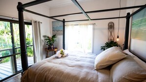 Un letto a baldacchino con vista su palme attraverso ampie finestre.