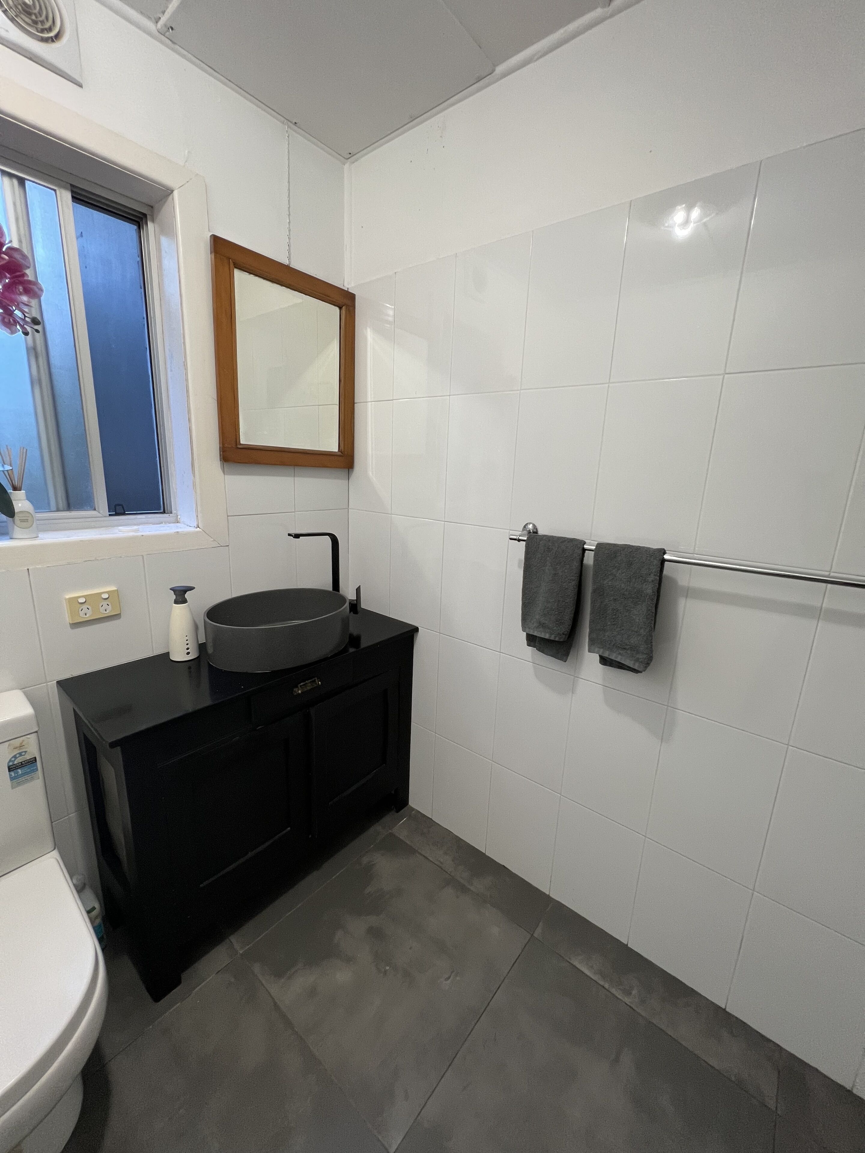 A bathroom with a toilet, a sink with a mirror above it, and a towel rack with two towels.
