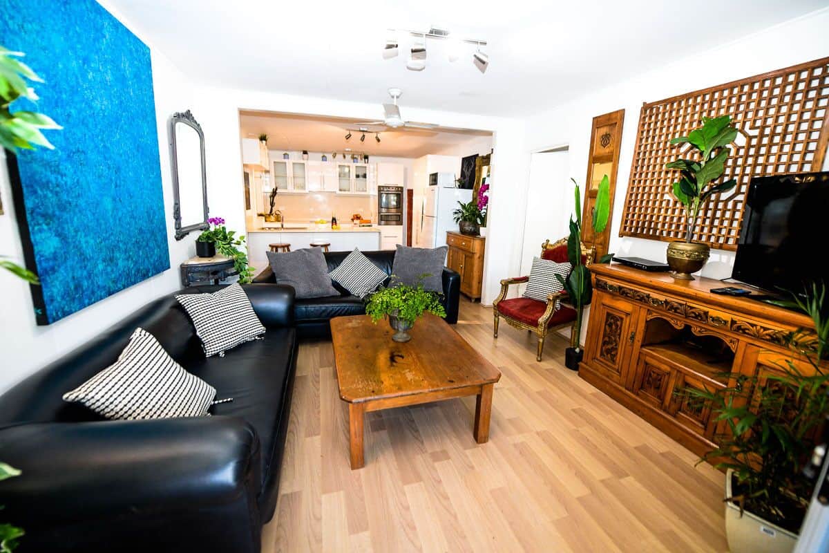 Ein modernes Wohnzimmer mit einem schwarzen Ledersofa, einem Holztisch und einem Fernseher auf einer Holzkommode.