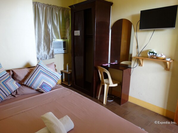 Une chambre d’hôtel équipée d’un lit, d’un bureau, d’une chaise, d’une télévision et d’un climatiseur.