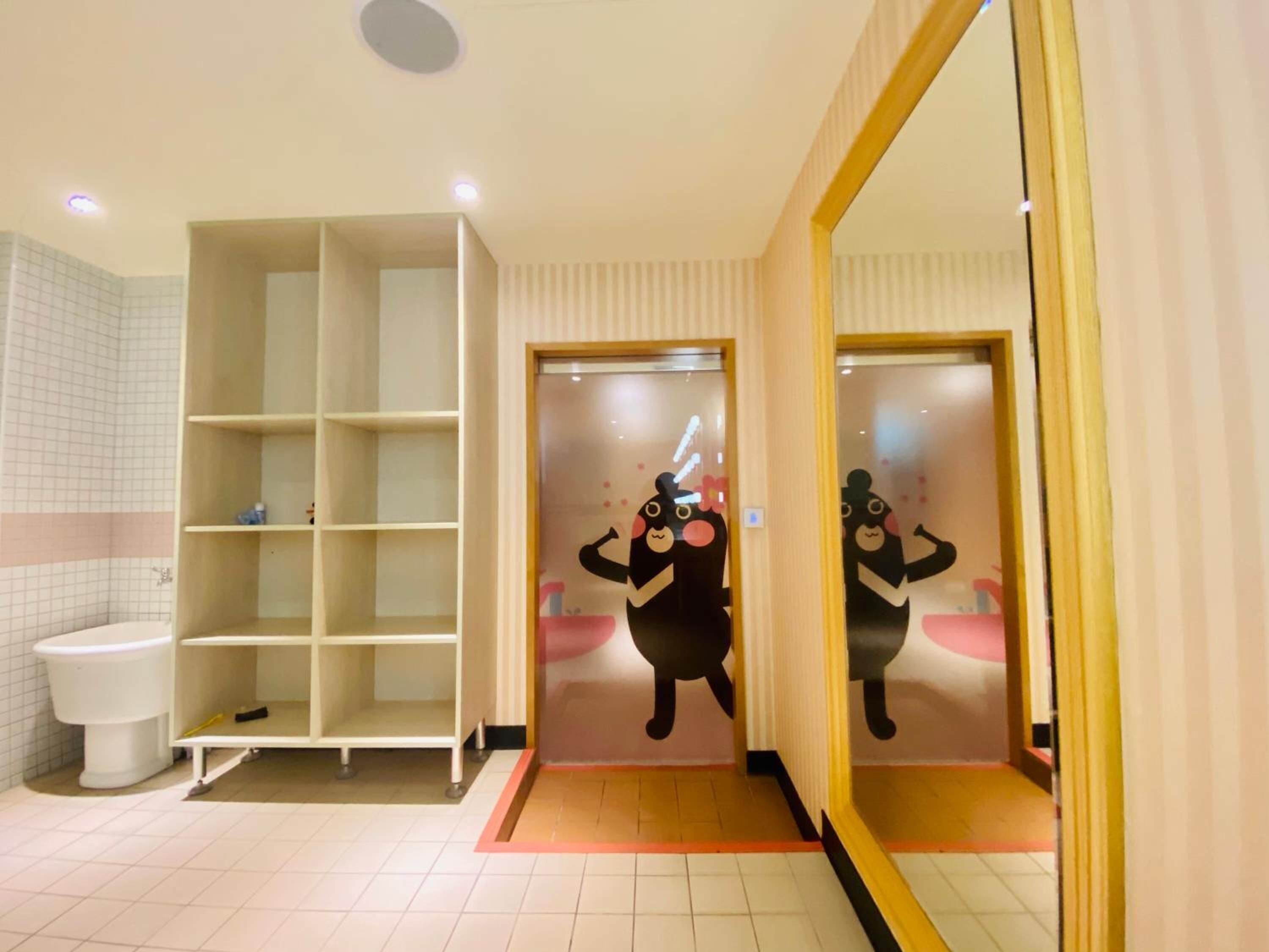 Een badkamer met een toilet, een wit schap en een spiegel.
