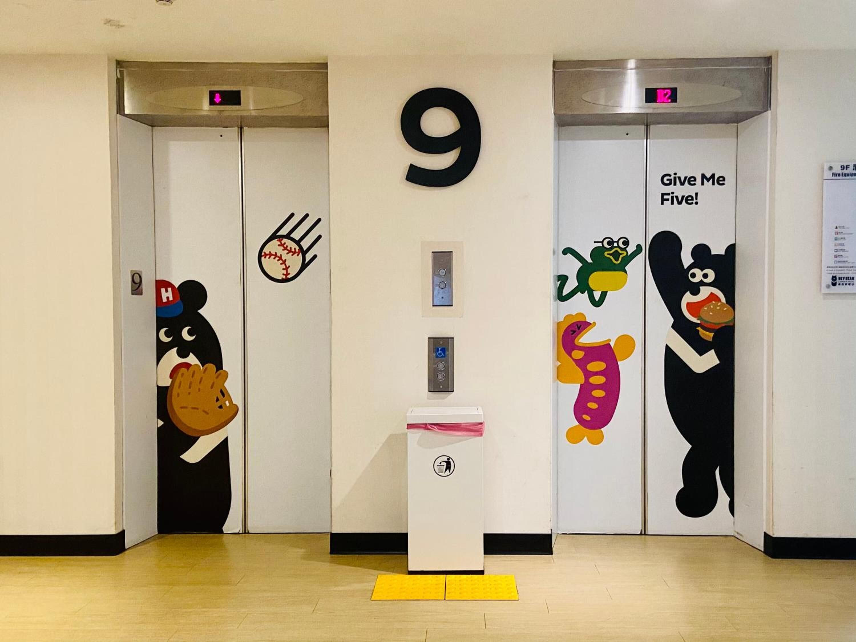 A hallway with two elevators, each with a number 9 and a playful cartoon character.