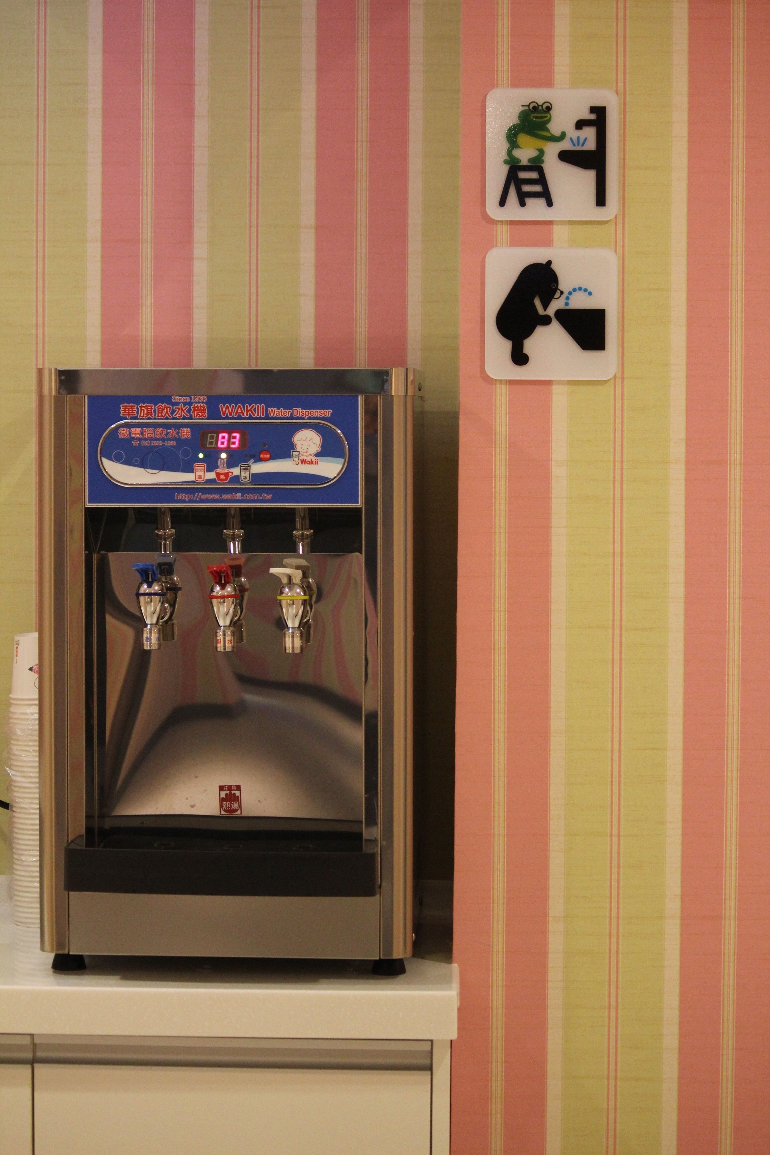 A water dispenser with three spouts, a digital display, and a red label.