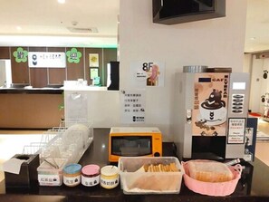 A counter with a coffee machine, a microwave, and various food items. - Heybear Capsule Hotel (New Taipei City)