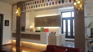 A reception area with a wooden reception desk, a sign reading "FOMEC'S BOUTIQUE HOTEL," and a colorful wall decoration above the desk. - Fomecs Boutique Hotel, Jonker Street (Malacca City)