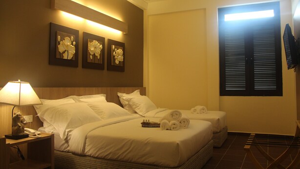A hotel room with two beds, a nightstand with a lamp, a wall-mounted TV, and artwork above the beds. - Fomecs Boutique Hotel, Jonker Street (Malacca City)