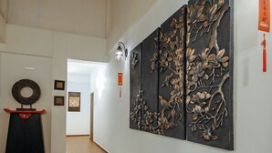 A hallway with a large wall-mounted artwork depicting branches and leaves, a circular decorative object on a pedestal, and a red hanging ornament. - Fomecs Boutique Hotel, Jonker Street (Malacca City)