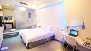 A modern hotel room with a bed, a desk, and a laptop.