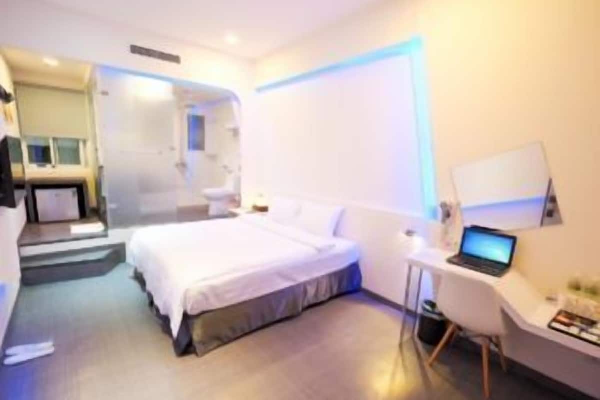 A modern hotel room with a bed, a desk, and a laptop.