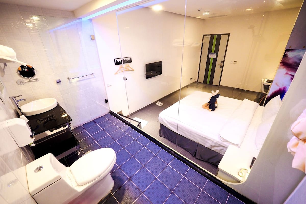 A hotel room with a bed, a bathroom with a sink and toilet, and a mirror.