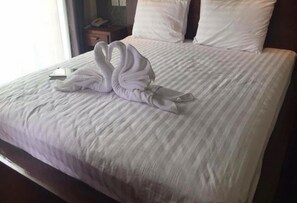Cama bem arrumada com uma toalha disposta em forma de cisne sobre o lençol.