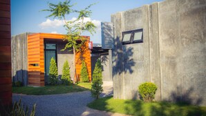 A modern building with a concrete facade, a wooden slatted entrance, and a sign indicating an exit. - The Infinite Resort Nakhon Sawan (Nakhon Sawan)