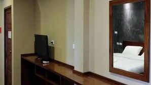 A hotel room with a wooden desk, a computer, a bed with a white mattress, and a mirror on the wall. - The Infinite Resort Nakhon Sawan (Nakhon Sawan)