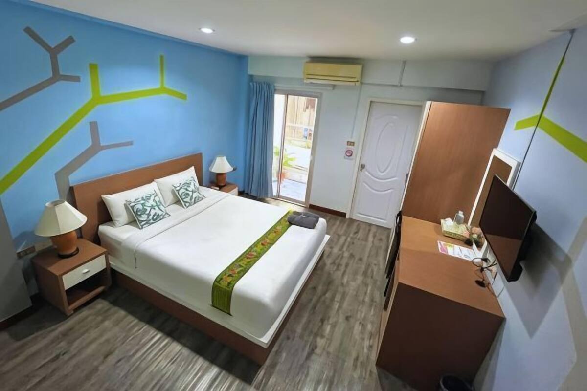 Ein Hotelzimmer mit Bett, Nachttischen, Schreibtisch und Fernseher.