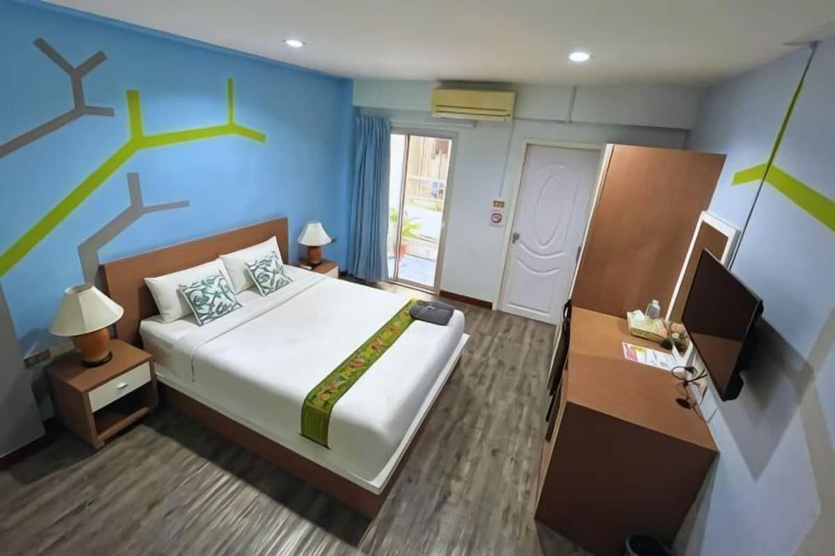 A hotel room with a bed, nightstands, a desk, and a TV.