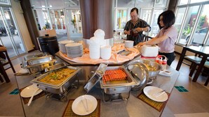 Buffet montado com diversas estações de comida, incluindo cachorros-quentes, saladas e uma estação de sopas.