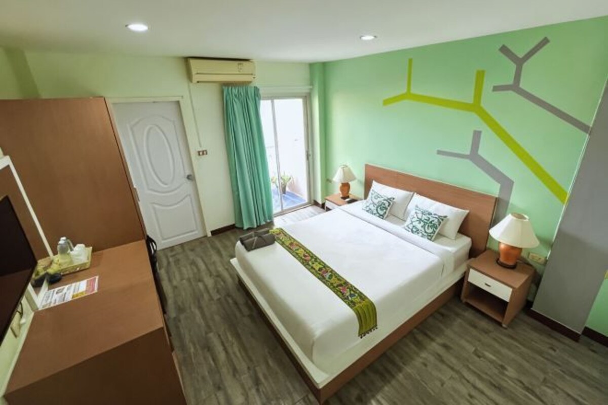 A hotel room with a bed, bedside table, lamp, and a wardrobe.