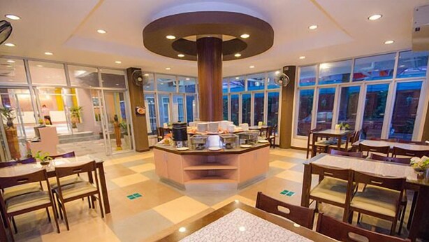 Um amplo hall de hotel com um bar de café central, várias áreas de estar e janelas grandes que oferecem vista do exterior.