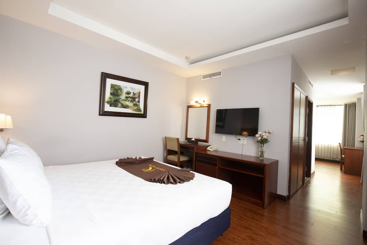 Une chambre d’hôtel avec un grand lit, un bureau avec un ordinateur, une télévision et un miroir.