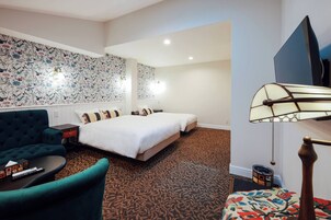 Una habitación de hotel con una cama grande, un sofá, una mesita y una alfombra estampada.