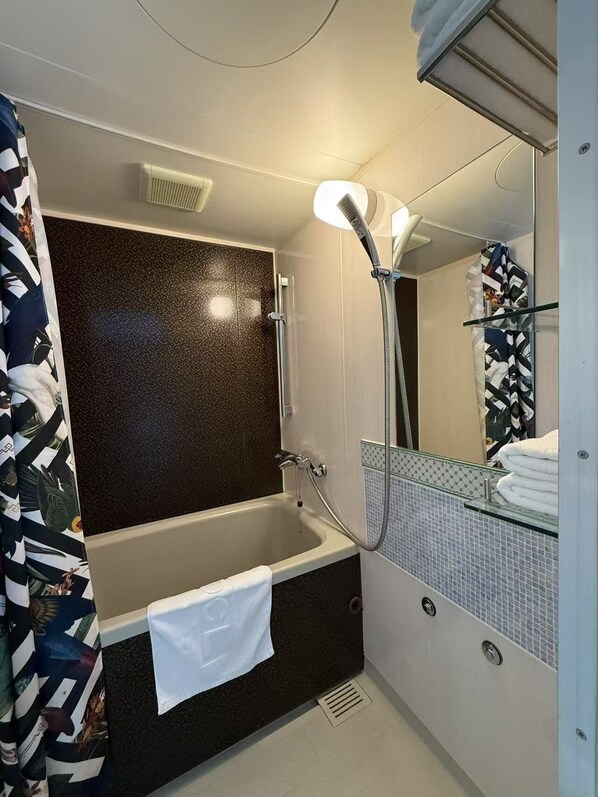 Un baño con bañera, ducha, espejo y toallero.