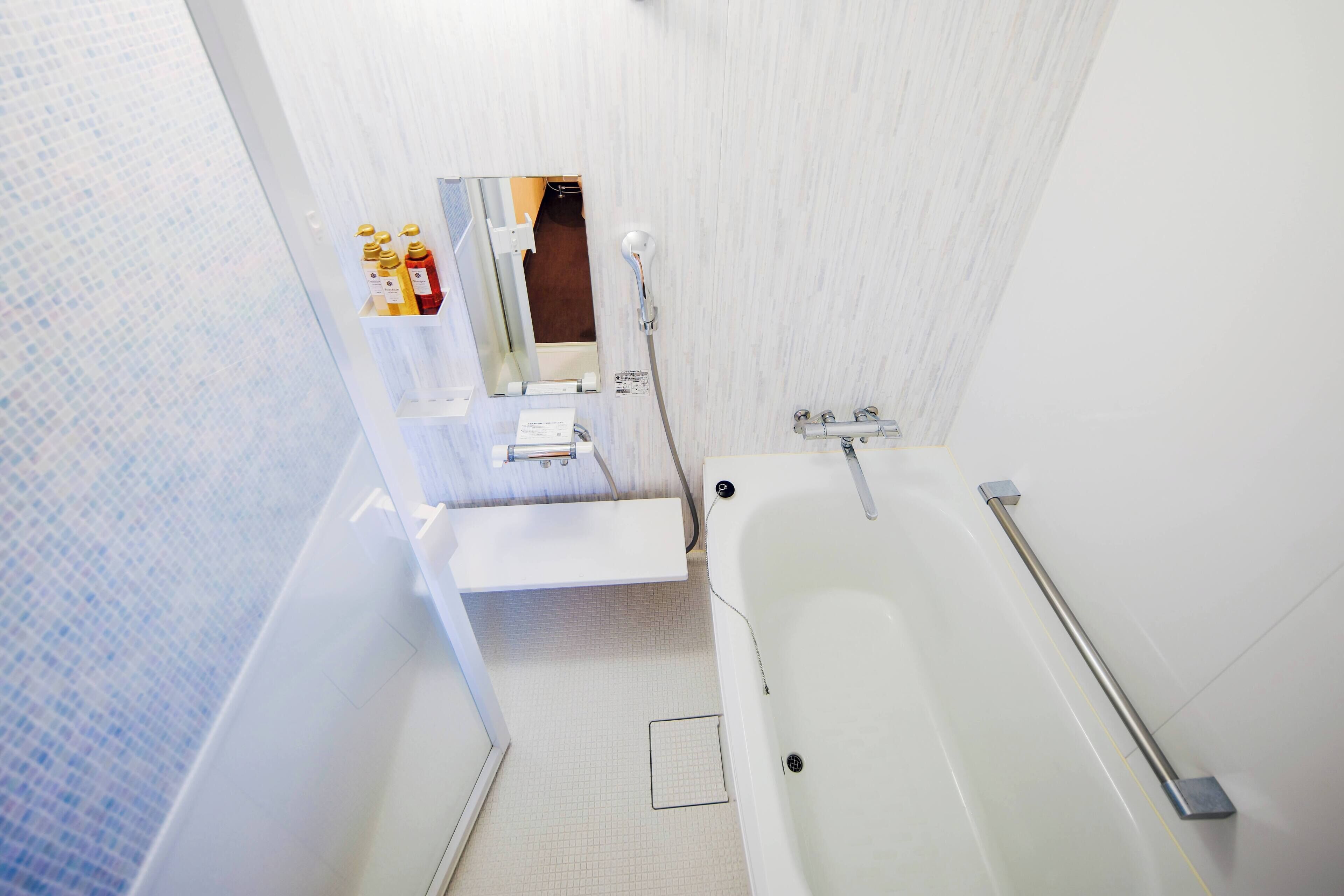 Ein modernes Badezimmer mit einer weißen Badewanne, einem Spiegel und einem Ablagefach für Pflegeprodukte.
