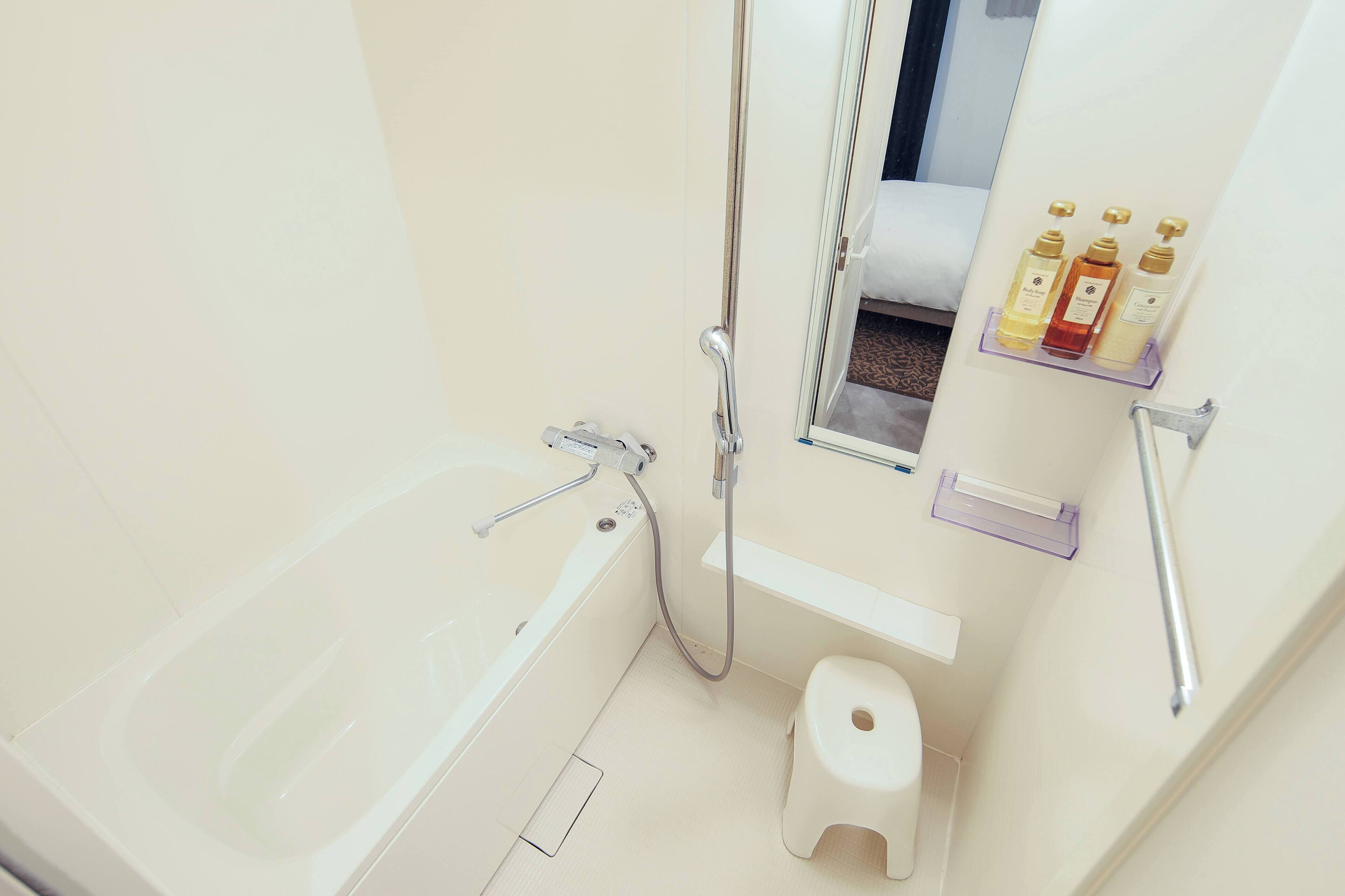A modern bathroom with a bathtub, a shower, a toilet, and a shelf with toiletries.
