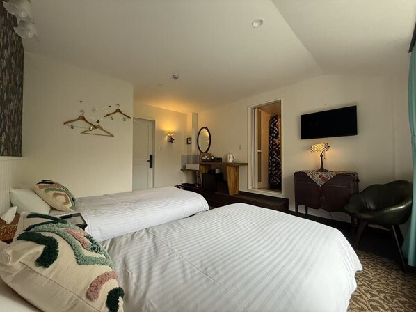 A hotel room with two single beds, a desk with a chair, a television, and a bathroom visible through an open door. - Hotel WELLIES (Karuizawa)