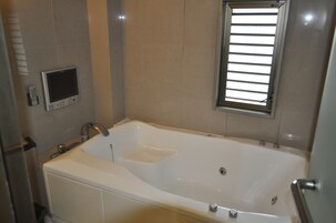 Un baño moderno con una bañera grande, un calentador integrado y una ventana con persianas.