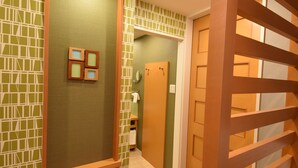 A hallway with a green patterned wall, a wooden partition, and a mirror. - HOTEL WOO - Adults Only (Yamatotakada)
