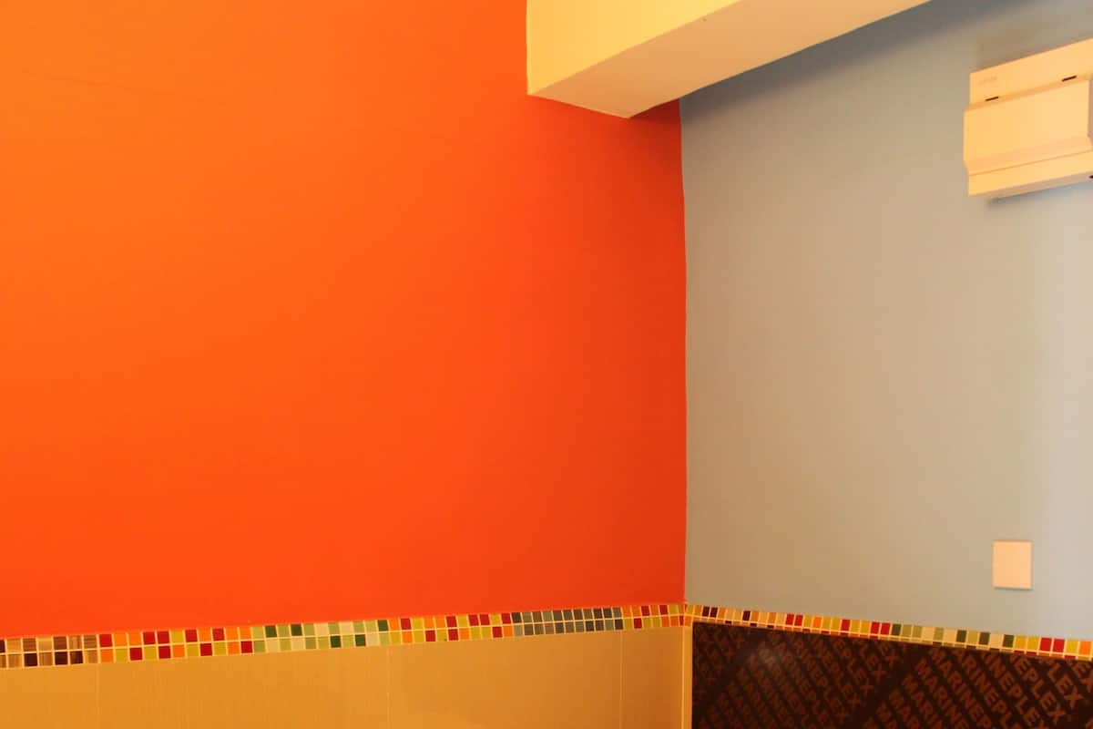 A room with a bed, orange and blue walls, and a patterned headboard.
