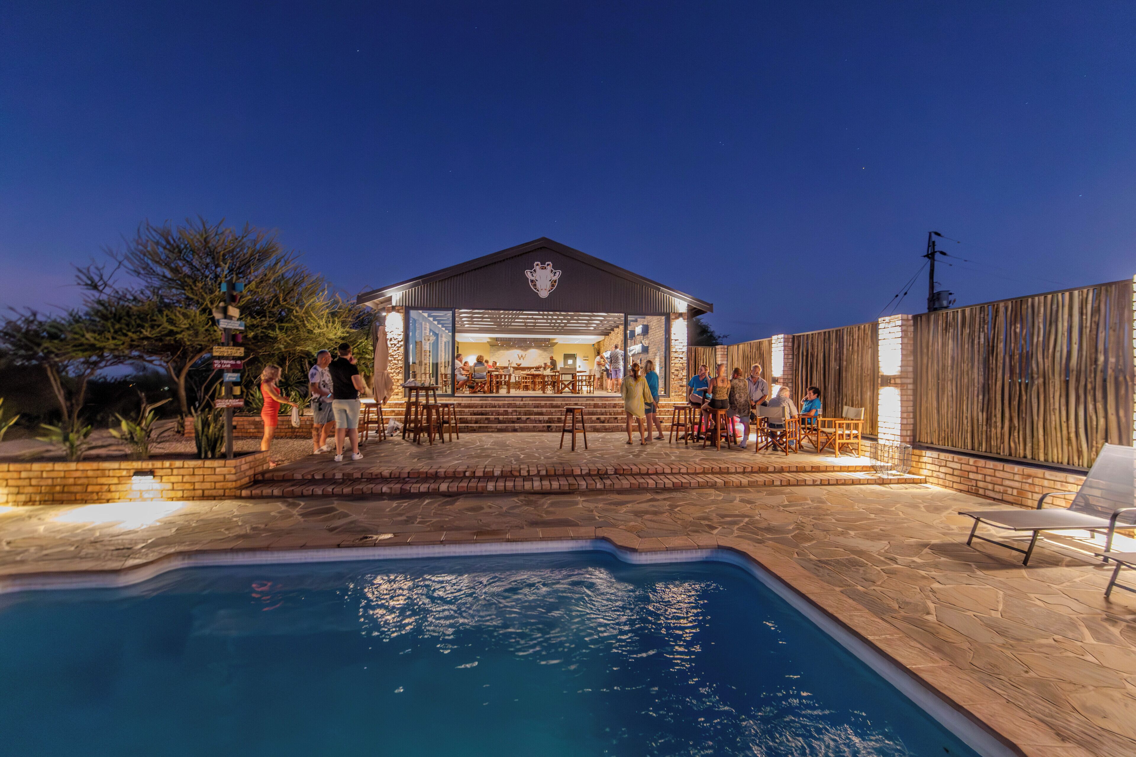 Zona de piscina exterior con bar y asientos, rodeada por una valla de madera y paredes de piedra.