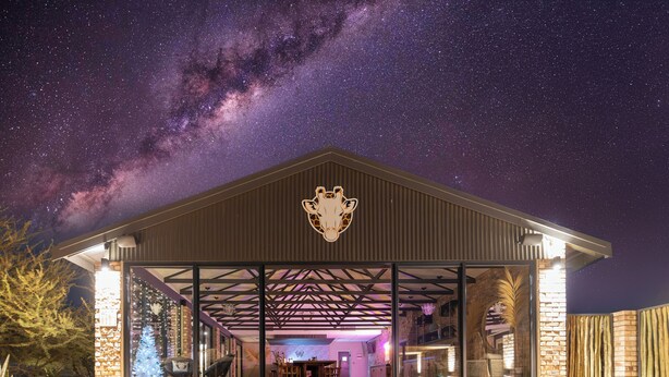 A building with a giraffe logo, large glass windows, and a brick exterior. - Windhoek Game Camp (Windhoek)