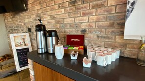 A coffee station with two thermos flasks, a mug, Twinings tea boxes, and a menu board. - Windhoek Game Camp (Windhoek)