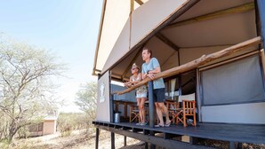 A two-story building with a balcony, wooden deck, and outdoor seating area. - Windhoek Game Camp (Windhoek)