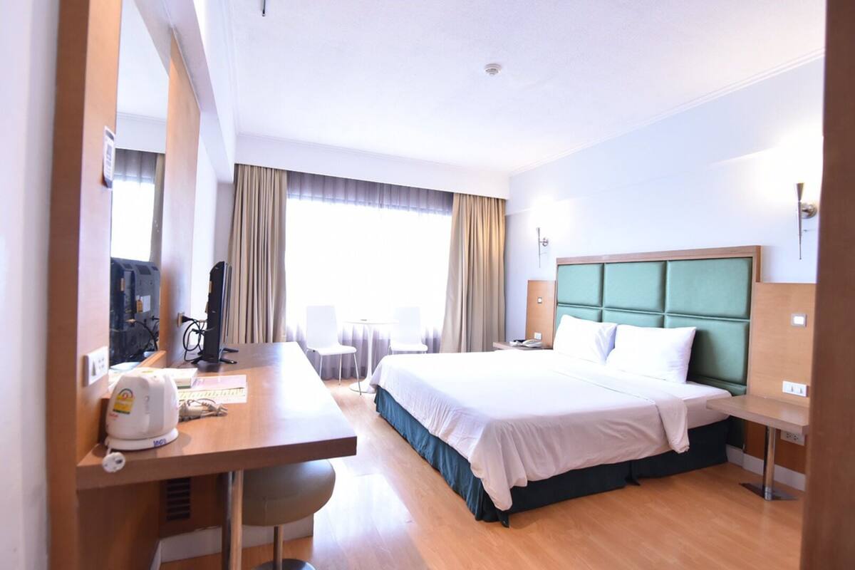 Une chambre d’hôtel équipée d’un lit, d’un bureau, de chaises et d’un téléviseur.