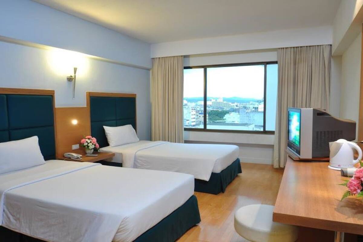 Une chambre d’hôtel avec deux lits, un bureau avec une télévision, une machine à café et une vue sur la ville.